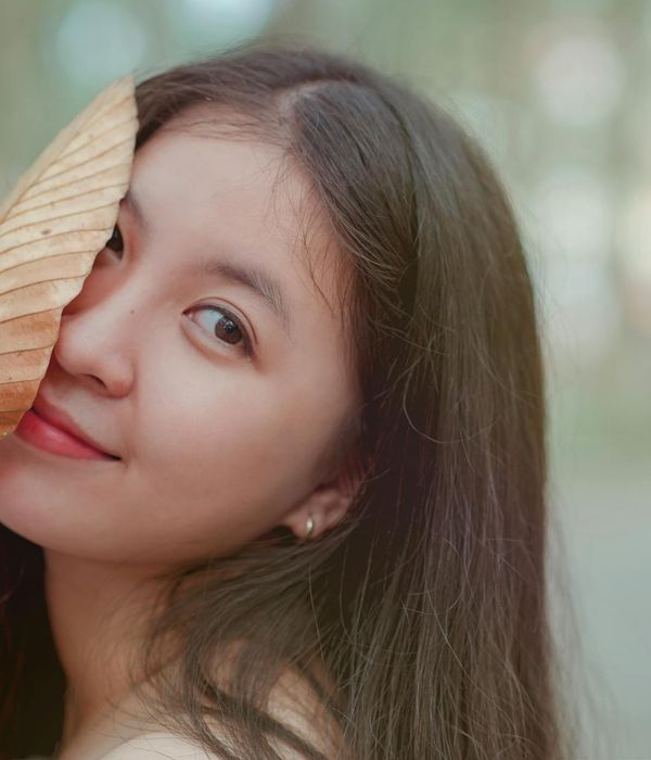 Serene woman with eyes closed in a peaceful natural setting.